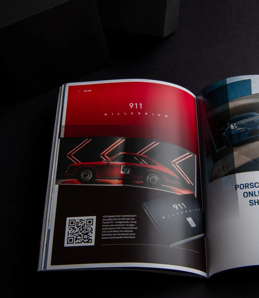 Aufgeschlagene Porsche Times zeigt eine Doppelseite zur Sonderedition 911 Millennium mit rotem Porsche und stilisierter Lichtinszenierung.