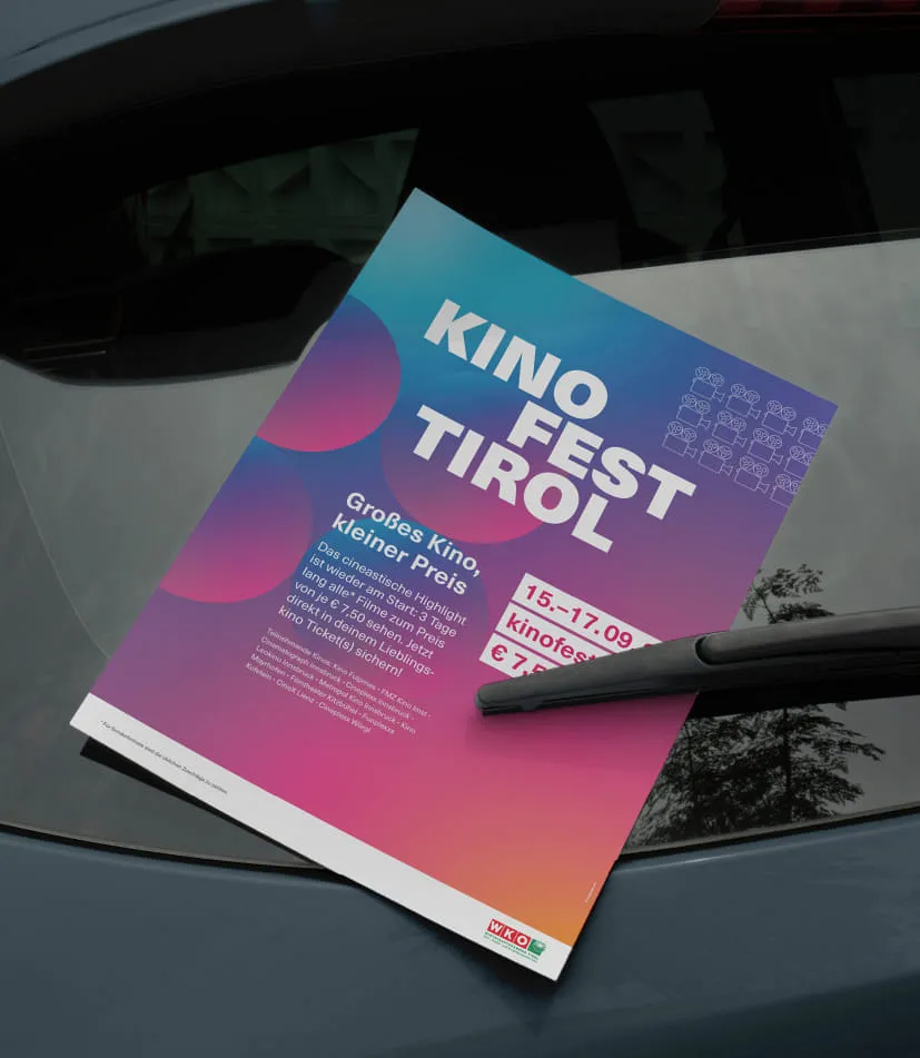 Auf der Heckscheibe eines dunklen Autos ist der Event Flyer des Kino Fest Tirol eingeklemmt.